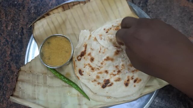 Indian flatbread such as parota or naan served with flavorful gravy in a small bowl, representing traditional South Asian cuisine and delicious dining
