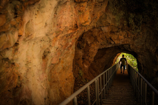 View of a hiker walking down a staircase through the rocky tunnel of French Mountain in Antsiranana, Diana, Madagascar.