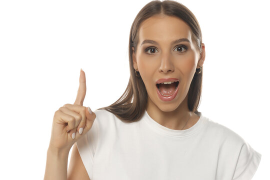 
Portrait of an excited woman with idea gesture, finger pointing up, mouth open, makeup, on white background.