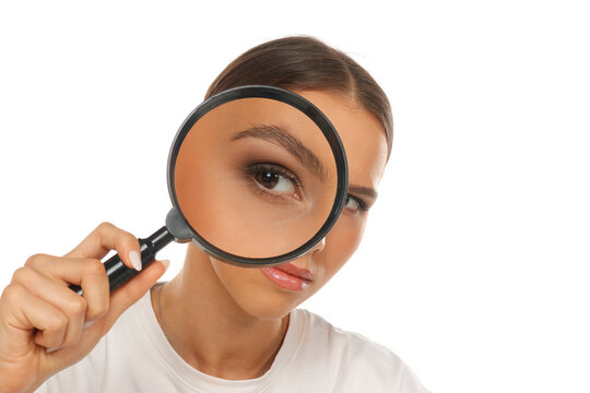 Portrait of woman holding magnifying glass over eye, detective search concept, on white background.
