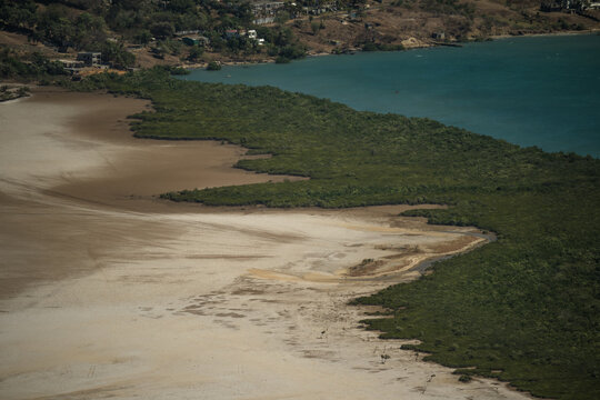 View of the coastal landscape near French Mountain with lush mangroves, sandy tidal flats, and turquoise waters in Antsiranana, Diana, Madagascar.