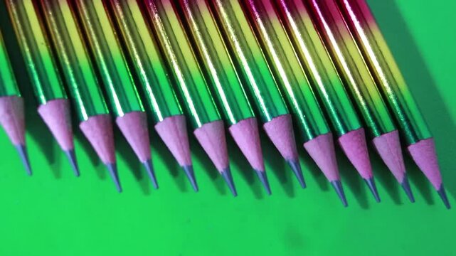 Rainbow gradient pencils are arranged in a precise row to create a vibrant artistic pattern in this smooth motion video
