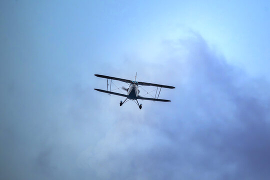 View of an aerobatic biplane flying through a cloudy sky in Cascais, Lisbon, Portugal.