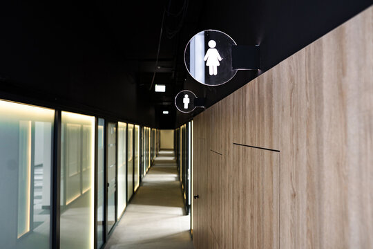 Building hallway showing gender specific toilet signs and wooden wall