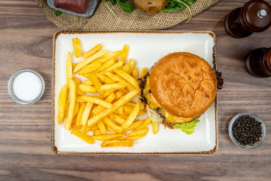 Cheeseburger served with crispy French fries, food flat lay, top-view on a rustic wooden table