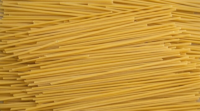 Texture of uncooked long yellow wheat noodles laid flat natural top view close up composition of traditional raw staple ingredient spaghetti pasta texture background noodles uncooked yellow raw dry