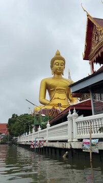 Bangkok, Thailand : View from moving longtail boat showing the Giant golden buddha statue of Wat Paknam Phasi Charoen during canal tour.