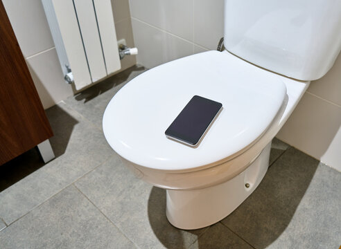 Bathroom scene toilet and phone on toilet seat at home
