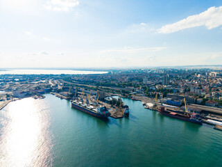 Fototapeta premium Boats docked at a busy port with city skyline in the background on a sunny day