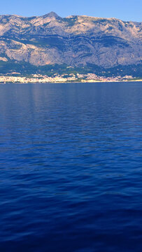 A serene adriatic sea view captures the tranquil coastline, perfect for summer vacation travel. The calm waters and distant mountains invite tourists to explore this picturesque beach destination.