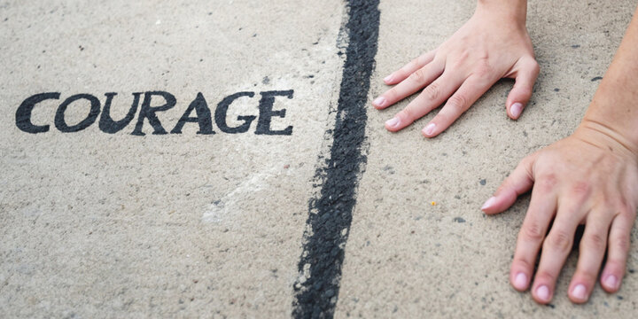 Overcoming fear and daring to take risks with my hands on the concrete behind the line painted next to the word COURAGE