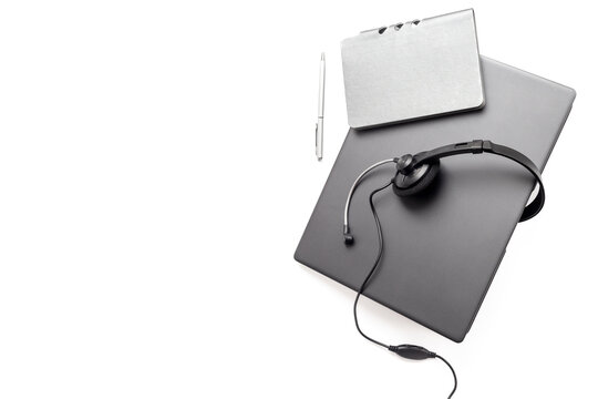 Remote customer support workspace - laptop with headset, and notebook in soft natural light, top view