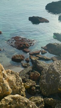 Clear turquoise water gently lapping on the rocky coast of Nerja, Spain during a calm sunny day