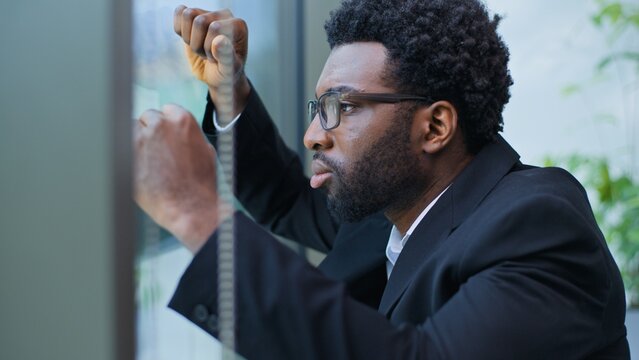 Close up worried annoyed stressed African American business man leaning window wall suffering with grief guy male businessman overworked suffer with losing job problem thinking hard decision in office