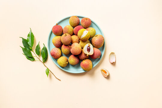Exotic lychee fruit with green leaves on plate, top view. Healthy vegetarian meal