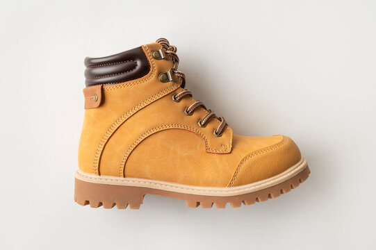 Brown leather boots on gray background, top view. Stylish autumn footwear, rough work boots. Men's, children's, or teenage footwear. Thick-soled boots with laces. Fashion, style, wardrobe essential.