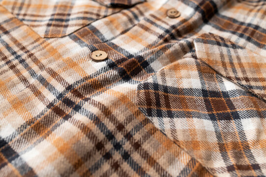 Close-up of details of plaid flannel fall shirt. Buttons, collar, sleeves, cotton plaid fabric in brown, red, beige tones. Fashionable, stylish clothing concept, texture of cozy fabric.