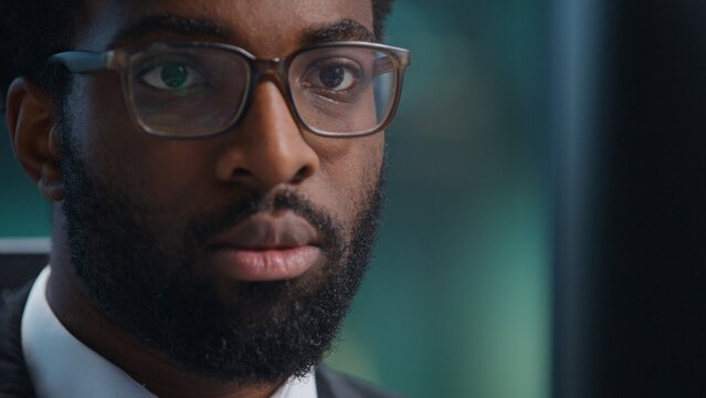 Close up African American business man serious looking in computer monitor in office. Portrait ethnic businessman male guy executive employer entrepreneur executive concentrated look in screen indoors