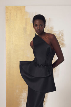 Close-up of a Black woman wearing asymmetrical one-shoulder structured black satin top