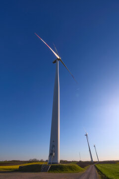 Wind turbines at sunset in green field &ndash; renewable energy, clean power, sustainable future.