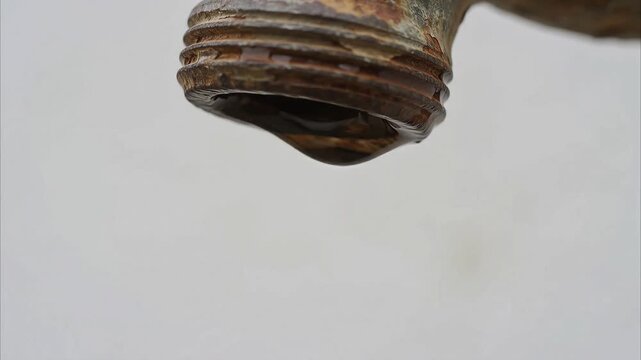 The last clear water drop falling from a rusty faucet, drought in Asia concept, isolated on white background, realistic 8K.