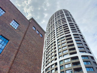 Fototapeta premium Modern building next to brick structure during cloudy day in an urban area