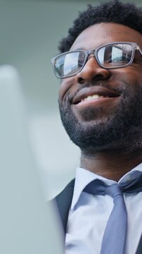 Close up carefree positive African American business man with laptop smiling typing device in office optimistic businessman male guy executive happy smile working with computer satisfied chatting