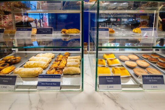 Cascais, Portugal - 22 August 2026: View of a bakery display case filled with traditional Portuguese pastries including Travesseiro de Sintra and Pastel de Nata.