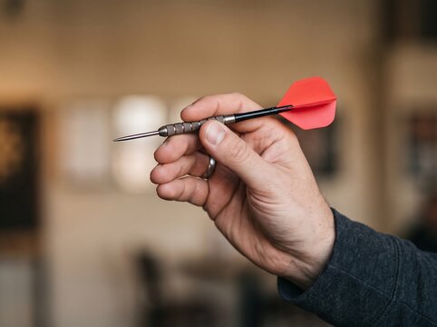 Person Holding Dart With Red Fletching Indoors