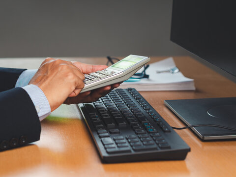 Hands Using Calculator at Computer Desk