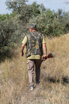 A hunter with a gun in camouflage clothing. A gentleman with a gun, medium shot, unrecognizable.