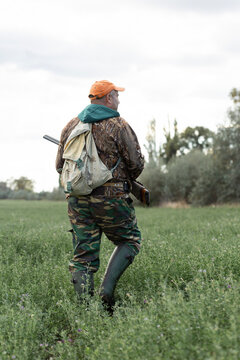 A hunter with a gun in camouflage clothing. A gentleman with a gun, medium shot, unrecognizable.