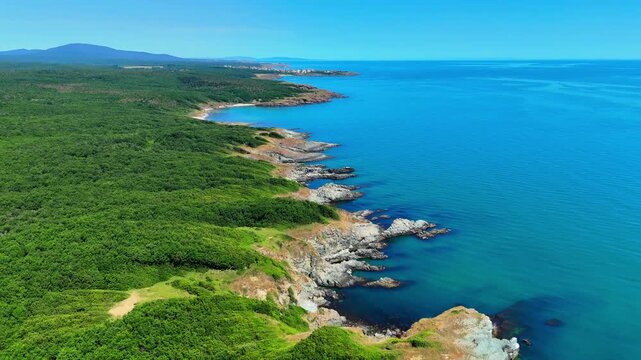 Wide aerial view of a secluded sandy beach with clear turquoise water, rocky shoreline and dense green vegetation along Bulgaria&rsquo;s southern Black Sea coast.