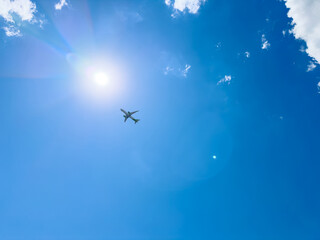 Naklejka premium Airplane flying in a clear blue sky under the bright sun during daytime