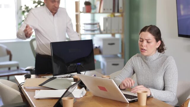 Young businessman of a large company, scolds his employee girl sitting at workdesk in the office . High quality 4k footage