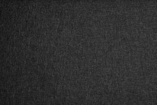 Close-up of dark grey fabric texture background, charcoal woven cloth material surface for design backdrop.