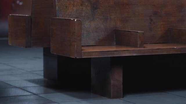 Wooden benches are placed in a quiet part of a modern building. The daylight shines on the smooth floor tiles. The benches have a simple design with sturdy legs.