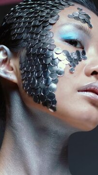 Vertical video: Rotating model as camera moves, tilting at studio, showcasing silver discs