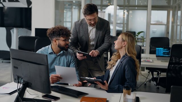 Multiethnic business team work group working discuss papers documents data talking with Caucasian boss company CEO with digital tablet three multiracial workers office colleagues with paperwork talk