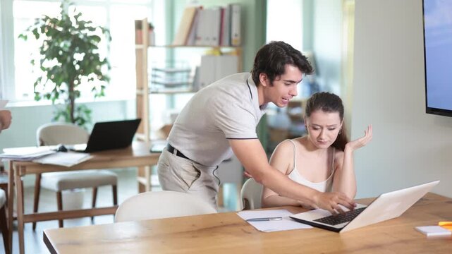 Young businessman of a large company, scolds his employee girl sitting at workdesk in the office. High quality 4k footage