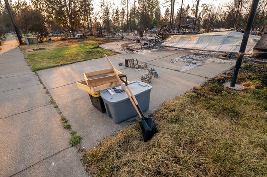 Spokane, Washington, United States - 14 August 2026: View of debris and sifting tools on a driveway after the Spokane wildfires, with scorched trees and remnants of a destroyed home.