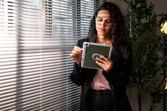 Portrait of businesswoman using a tablet and stylus in a modern office
