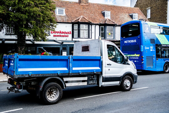 Small Business Utility Ford Transit Flatbed Truck Driving On A town Centre Main Road