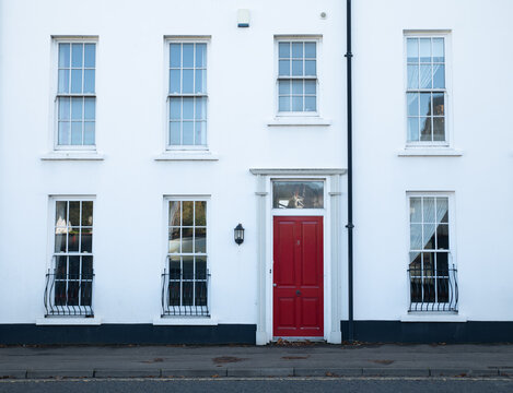 Ballycastle, Northern Ireland, United Kingdom - 07 July 2020: View of a white building facade featuring a prominent red front door and traditional sash windows.
