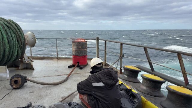 Close-up of a deckhand sorting waste and burning it safely on a moving vessel in the ocean. Concept of maritime ecology and keeping oceans clean.