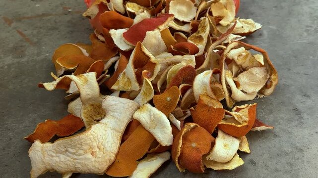 Dried orange peels piled on grey concrete floor, citrus rind waste or ingredient