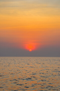 Kampong Phluk, Siem Reap Province, Cambodia - 05 February 2020: View of the sunset over Tonle Sap lake with calm water reflecting the orange and red sky.
