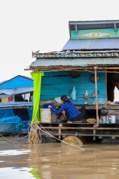 Kampong Phluk, Siem Reap Province, Cambodia - 05 February 2020: View of a woman preparing food on the porch of a traditional floating house on Tonle Sap lake.