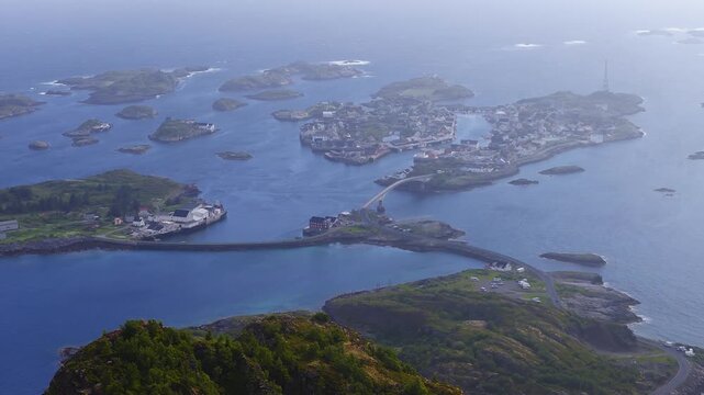 High altitude aerial footage showcases the archipelago settlement of Henningsvaer connected by bridges in Lofoten, Norway on a clear day.