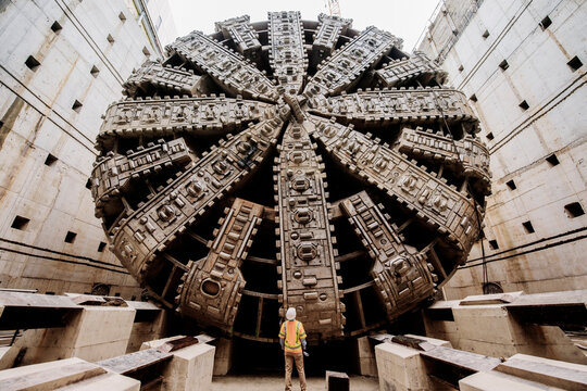 A white worker inspects a massive tunnel boring machine